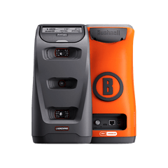 Two golf launch monitors, one black with "LAUNCH PRO," one orange with "Bushnell" and a "B" logo. They stand side-by-side.