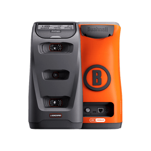 Two golf launch monitors, one black with "LAUNCH PRO," one orange with "Bushnell" and a "B" logo. They stand side-by-side.